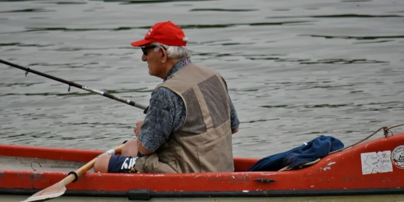 Hombre con una caña de pescar en un kayak rojo sobre el agua