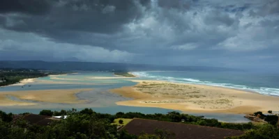 Vista de la laguna, la playa y el océano en Plettenberg Bay bajo oscuras nubes de tormenta