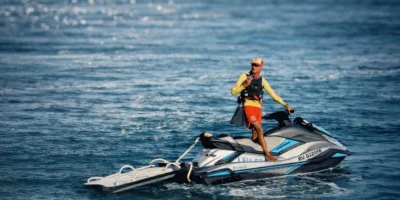 Un socorrista de RESSAC está de pie sobre una moto acuática frente a la costa de La Reunión