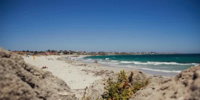 Bañistas y olas en Sorrento Beach, con rocas en primer plano