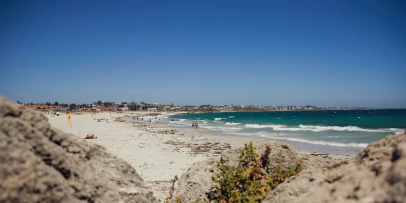 Bañistas y olas en Sorrento Beach, con rocas en primer plano